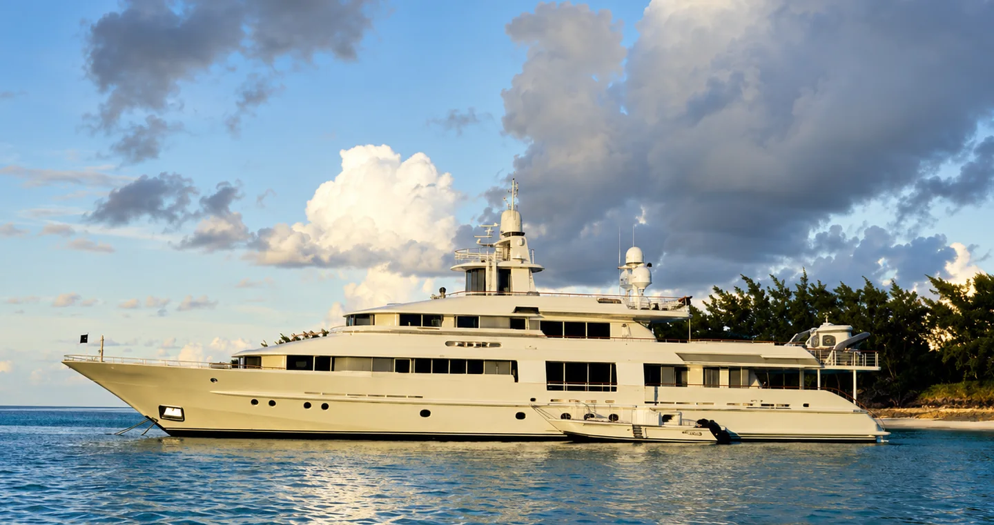 Large private yacht anchored beside a tropical shoreline
